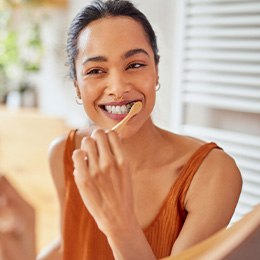 Woman smiling while brushing her teeth