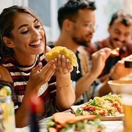 Woman smiling while eating lunch with friends at restaurant