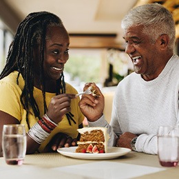 Couple smiling while enjoying slice of cake together